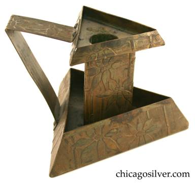 Carence Crafters candleholder, brass, composed of triangular copper base with sides that angle up and inward, large triangular central shaft, and smaller triangular drip-tray that also angles up and in.  Angular strap handle. Surfaces acid etched with floral design.