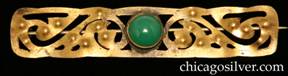Forest Craft Guild brooch, brass, rectangular, with rounded corners, extensive curving cutouts, and numerous small repousse domes, centering a round green bezel-set cabochon stone.
