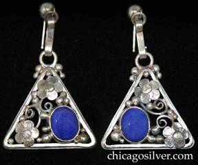 Laurence Foss earrings, drop, for pierced ears, on a stepped triangular frame, with an applied five-petal flower at the top and outside corners, delicate applied bead and wirework ornament, and an oval bezel-set cabochon lapis stone on the inside corner.  The earrings are mirror-images of each other.  Each hangs from a silver ball with an S-shaped strap wire link beneath it.  