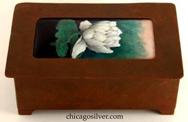 Frank Gardner Hale box, copper, rectangular, on four small applied feet at the corners with curved edges, hinged overlapping lid with rounded corners and large enameled rectangular domed insert in excellent condition.  Enameled decoration is detailed creamy white water lily blossom above rich green leaf, on background that varies from deep black at the bottom to mottled green and then light rose at the top.  Nicely hammered.  