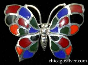 Kalo brooch / pin, butterfly-shaped, with detailed insect body and antennae surrounded by four-part wings decorated with cloisonn enamel cells in blue, orange, black, red, and green colors