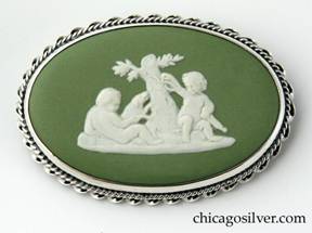 Kalo brooch, oval frame open on the back, with gadrooned twisted cable border decoration, centering a piece of green bezel-set Wedgwood with classic motif