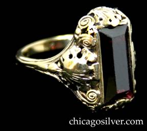 Ring, by Edward Oakes, yellow gold with scrolling foliate designs and spiraling curved wire on top and sides, centering large rectangular faceted garnet.  