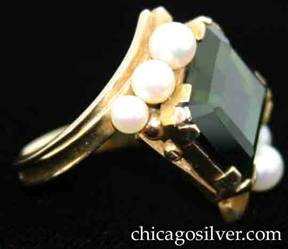 Ring, by Gilbert Oakes, handwrought in 14K gold with central faceted deep green tourmaline, flanked by 3 pearls.  The central tourmaline has been rotated so that when worn, the rectangular stone sits on the finger at an angle instead of the typical symmetric orientation.  Interesting, modern setting.