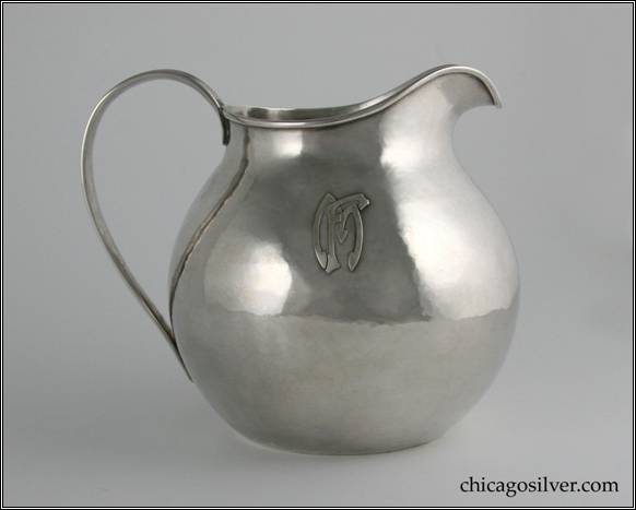 Kalo pitcher, water, round, flat bottom squat form with looping strap handle.  Hammered surface.  Applied FM mono on side.  6" H and 6-3/4" W.  STERLING / HAND WROUGHT / AT / THE KALO SHOPS / CHICAGO / AND / NEW YORK / 9309