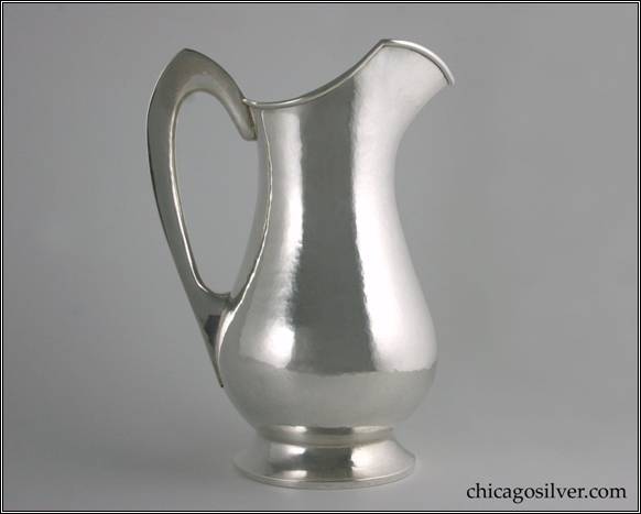 Kalo pitcher, tall and slender, on round spreading foot, with arching hollow handle with flat outside edge, pointed arch at top, applied wire to rim, high angular spout.  Nice hammering.  9-3/4" H and 7" W.  STERLING / HAND WROUGHT / AT / THE KALO SHOP / G873M / 3 PINTS
