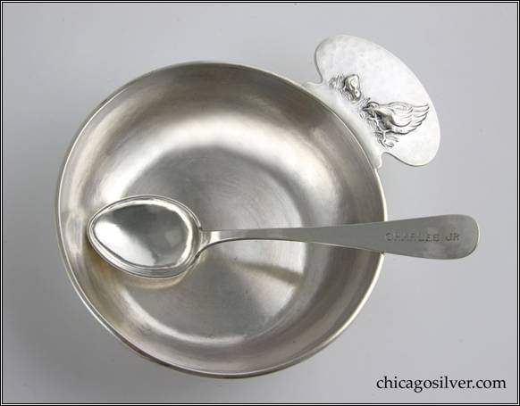Kalo porringer with applied wire to rim and rounded tab handle with chased and repouss decoration of hen and chick standing on grass, engraved "CHARLES JR" on side.  Matching spoon with heart-shaped bowl and rounded end, with engraved "CHARLES JR" on end