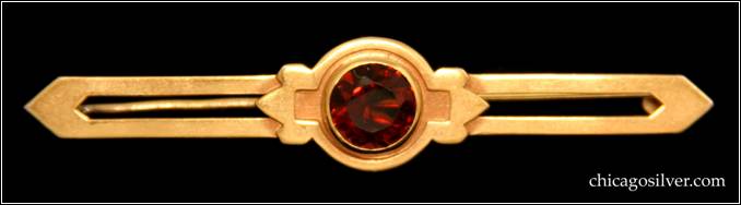 Kalo bar pin, gold, small, centering round faceted bezel-set garnet, with recessed area around stone that has square-shaped extensions on the sides surrounded by pointed details, with two long arms that have cutouts in the middle and points at the end.  2-1/2" L and 1/2" H.  Marked KALO 14K