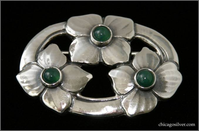 Kalo brooch / pin, oval, three large blossoms spaced evenly around a chased and cutout oval frame, each with four petals and each centering a dark green bezel-set round cabochon stone.  Nice hammering -- the blossoms have subtle texture lines extending from the center outward that are the result of delicate hand work.  1-7/8" L and 1-1/4" W.  Marked:  STERLING KALO