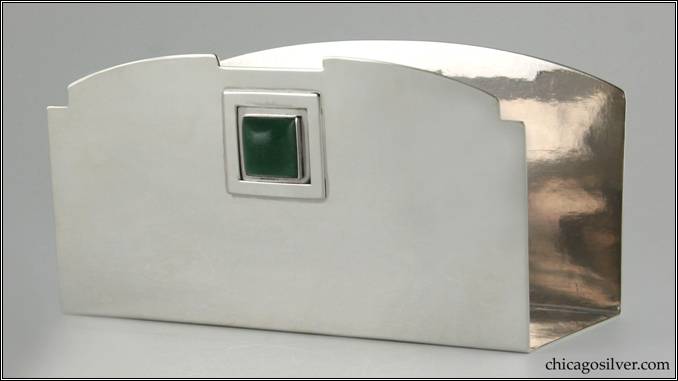 Kalo letter holder, silver, u-shaped, with flat bottom and straight front and back.  Top of back is curved.  Top of front matches the same curve but with small notches at the top corners and a large flat notch in the center.  Below this is a square applied frame centering a square bezel-set green cabochon stone.  Engraved on the underside is "October 12, 1910"  An early piece.  7-1/16" W and 3-5/8" H and 3-1/8" D.  HAND BEATEN / AT / KALO SHOPS / PARK RIDGE / ILLS. / 2722