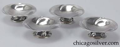 Peer Smed salts, set of four (4), round bowls with four evenly-spaced repoussé swirling decorations at the edge, on small spreading cutout feet that repeat the swirling form.