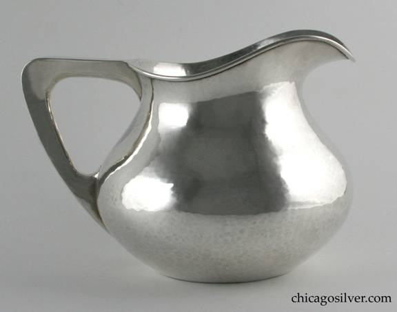 TC Shop water pitcher, squat, bulbous form with flat bottom, hollow harp-shaped handle, wide angular spout.