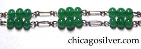 Detail from chain on pendant with sterling on chain with green stone.  Chain has alternating long and short loops, with additional detail of three groups of three small round green stone beads near the clasp on each side, six groups of three beads total (see similar mark on pin above).  Silver expert Fred Zweig points out that a similar mark (M in a diamond) is attributed in Dorothy Rainwater's Encyclopedia of American Silver Manufacturers to Mandalian Manufacturing Company, North Attelboro, MA.